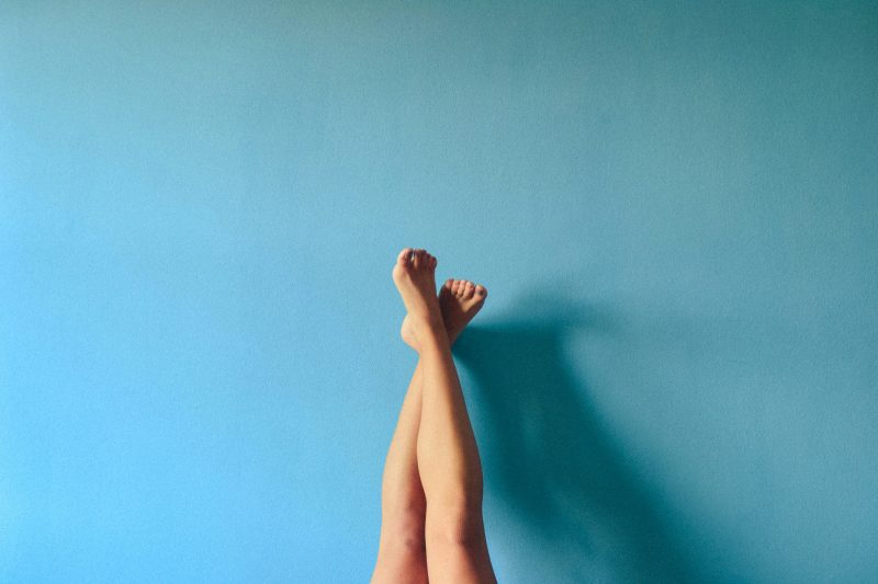Restless legs pose representing menopause symptom relief, with crossed legs upside down on the wall.