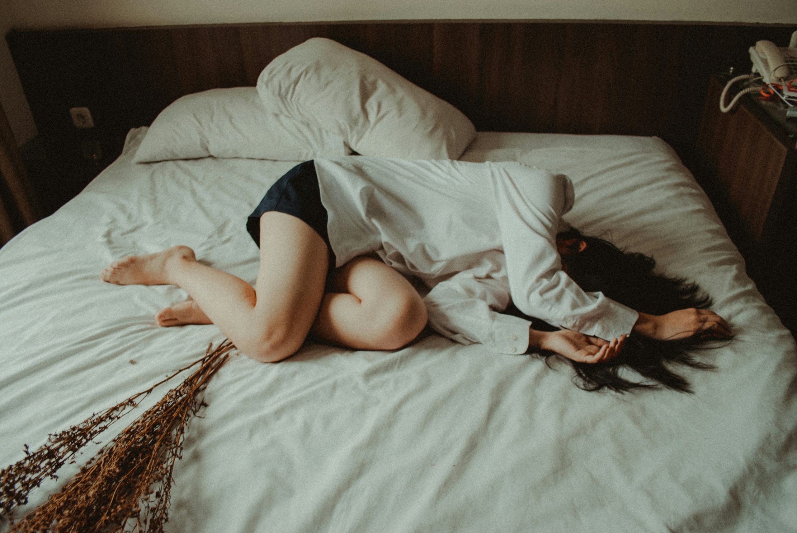 Woman lying on bed in exhaustion, overwhelmed by anxiety and depression.