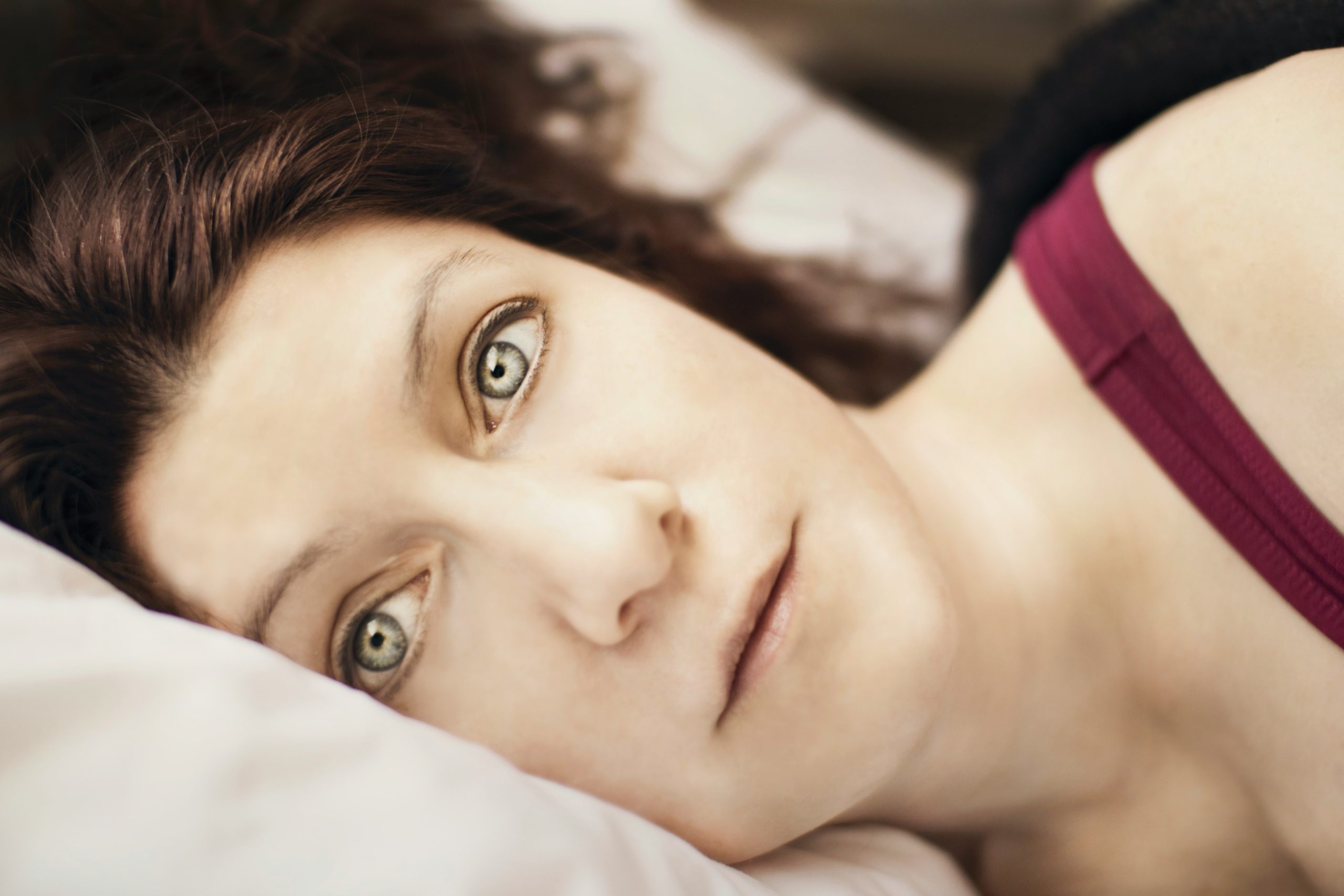 Woman lying in bed looking frustrated and emotionally overwhelmed, representing menopause mood swings, irritability, and hormonal changes.