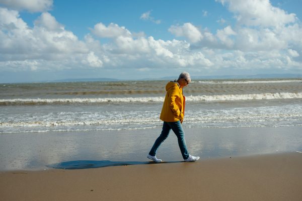 Woman walking along the beach during the day, embracing mindful movement for perimenopause wellness.
