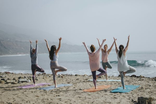 Woman practicing yoga on the beach with a group – gentle exercise for perimenopause wellness and hormone balance