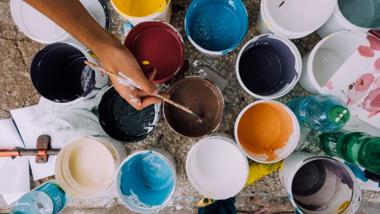 Messy art table covered in paints and open paint tins, symbolizing creative expression and emotional wellbeing during perimenopause.