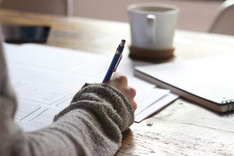 Woman journaling at a table during perimenopause to support mental health and wellbeing.