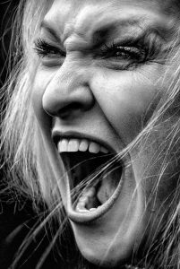Close-up of woman screaming, expressing hormonal rage and emotional overwhelm during perimenopause.