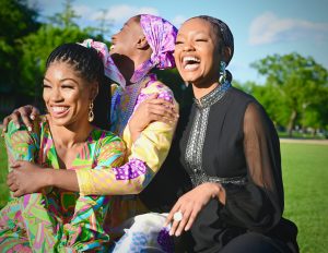 Three women laughing together outdoors in front of a hill. A joyful moment of friendship, support, and embracing life’s journey.
