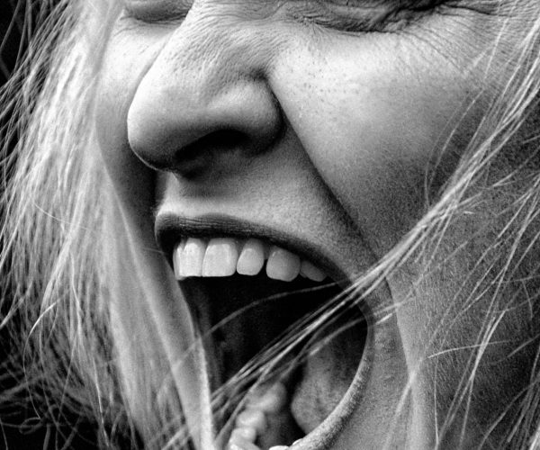 Close-up of woman screaming, expressing hormonal rage and emotional overwhelm during perimenopause.