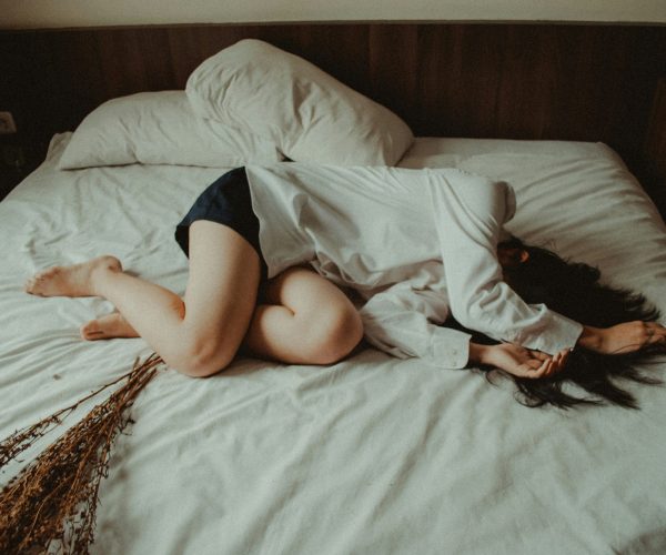 Woman lying on bed in exhaustion, overwhelmed by anxiety and depression.