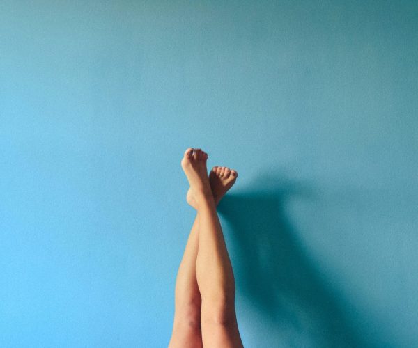 Restless legs pose representing menopause symptom relief, with crossed legs upside down on the wall.