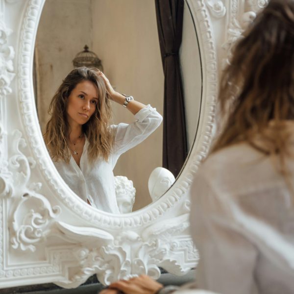 “Woman checking greasy hair in mirror, menopause hair changes”