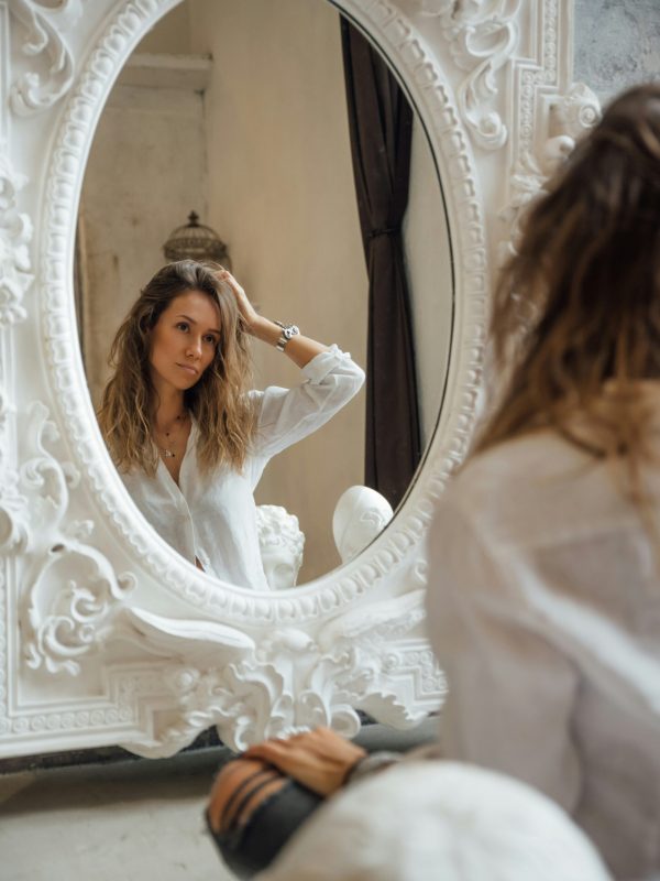 “Woman checking greasy hair in mirror, menopause hair changes”