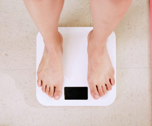 Menopause weight changes, woman standing on scales during menopause.